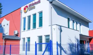 Nowoczesny budynek kliniki medycznej "Wiśniowa Clinic" z niebieskim ogrodzeniem.