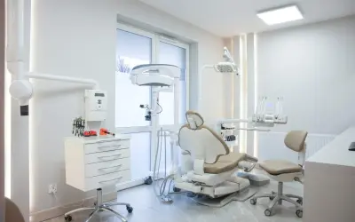 Nowoczesny gabinet stomatologiczny z fotelem dentystycznym i sprzętem.
