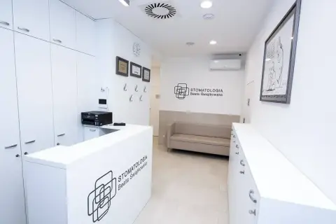 Nowoczesna recepcja gabinetu stomatologicznego z kanapą i logo.