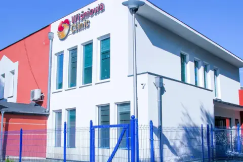Nowoczesny budynek kliniki medycznej "Wiśniowa Clinic" z niebieskim ogrodzeniem.