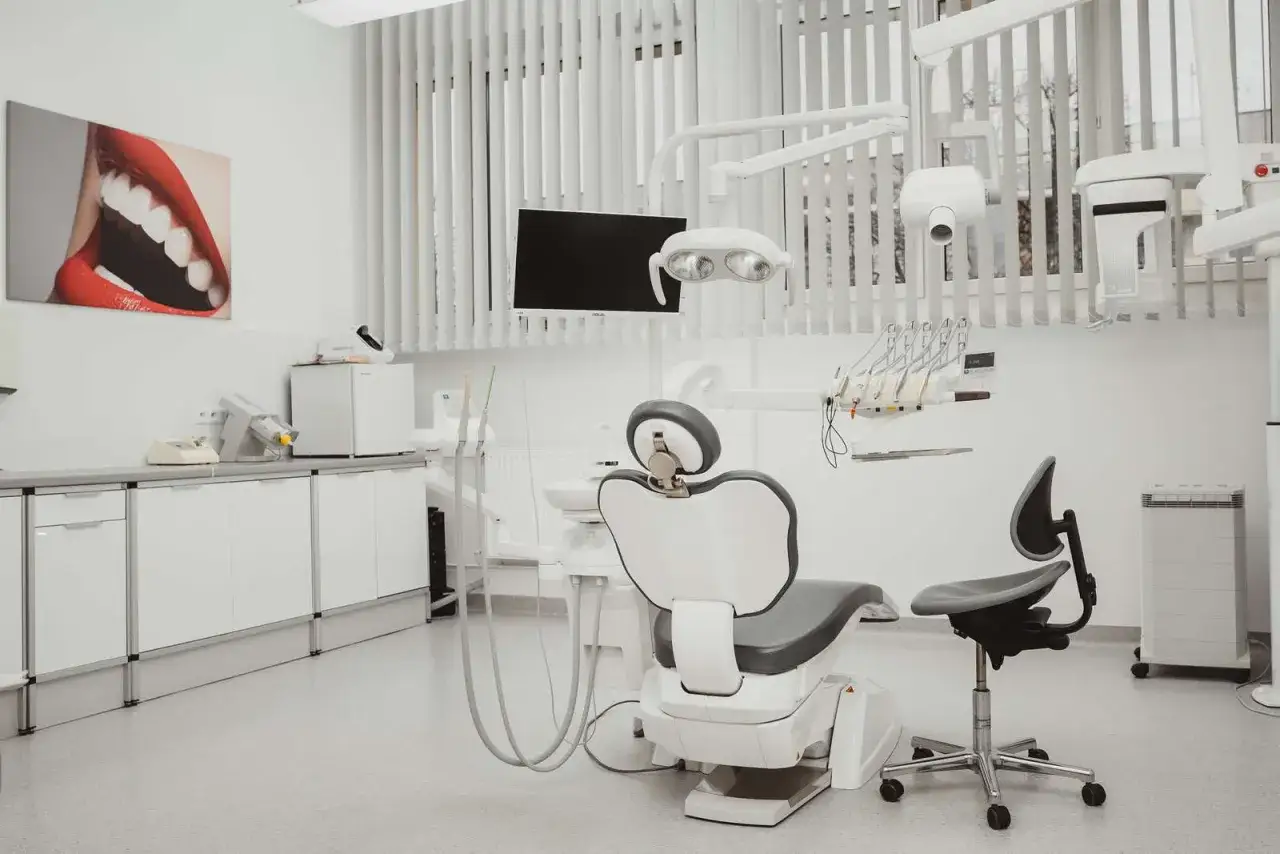 Nowoczesny gabinet stomatologiczny z fotelem dentystycznym, lampą i obrazem uśmiechu.