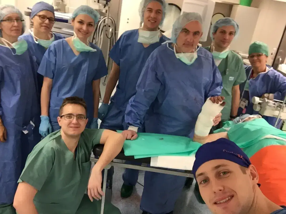 Zespół chirurgów w Gdańsku w strojach operacyjnych, jeden z nich trzyma zabandażowaną stopę.