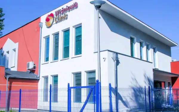 Nowoczesny budynek kliniki medycznej "Wiśniowa Clinic" z niebieskim ogrodzeniem.